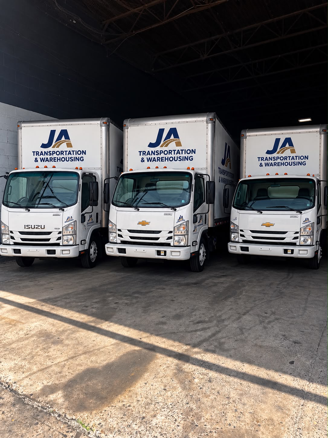 Three JA Transportation & Warehousing branded box trucks parked side by side at the Philadelphia warehouse